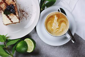 A coffee next to cake and a lime