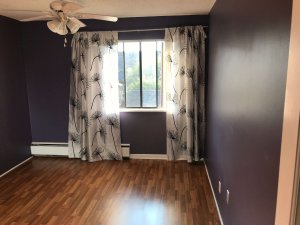 Photograph of my bedroom. Purple walls. Ceiling fan. Dark brown narrow laminate flooring.