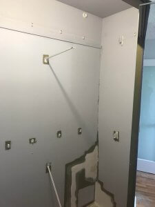 Photo inside the bedroom closet after some of the first coat of the light grey paint had been applied. Some of the holes have been patched. Some of the dark green is still visible.